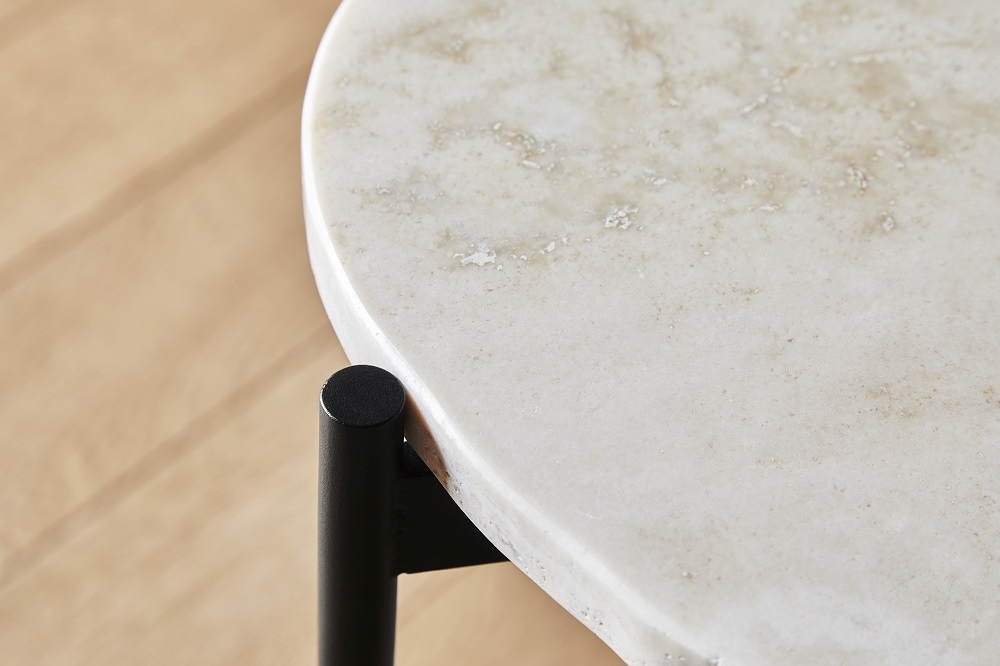Detailaufnahme: La Terra Couchtisch von Woud mit runder Marmorplatte und schwarzem Metallfuß.