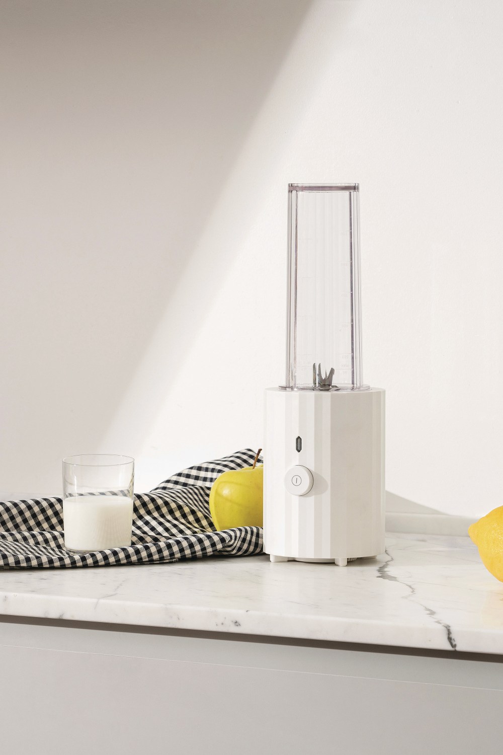 Weißer Alessi Plissé Smoothie Maker auf Marmor, mit Milch, Apfel und Zitrone.
