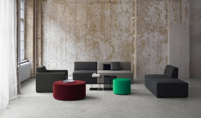 SF06 Kerman Modulsofa von e15 in modernem Design mit Sesseln und farbigen Hockern.