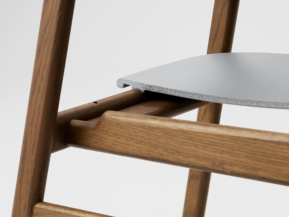 Detailaufnahme vom Herit Chair Stuhl von Normann Copenhagen: Holzrahmen und graue Sitzfläche im minimalistischen Design.