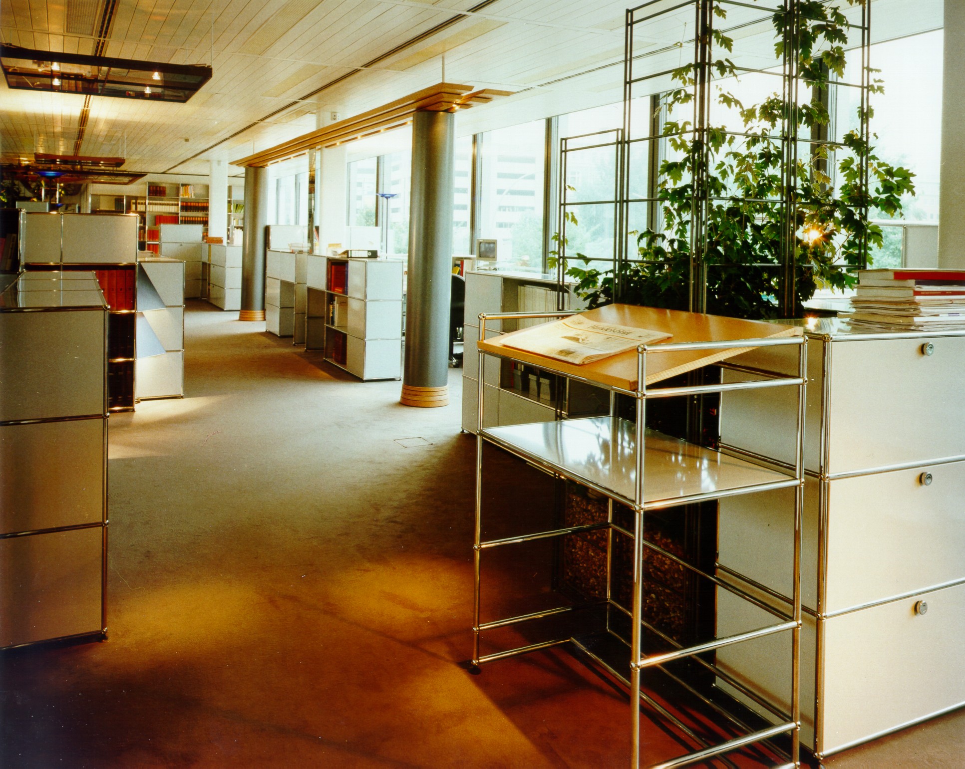 USM Haller Stehpult im Büroraum mit modularen Möbeln und viel Tageslicht, ideal für modernes Arbeiten.