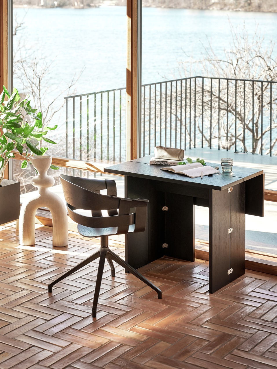 Design House Stockholm Flip Table Klapptisch aus dunklem Holz mit Stuhl vor Fenster.