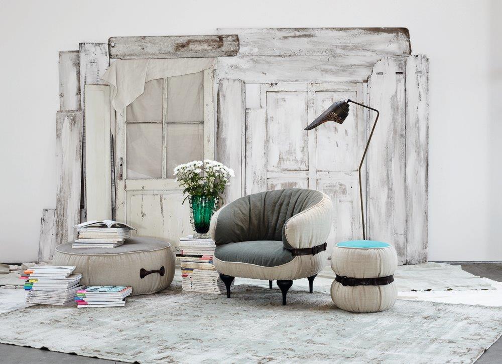 Gemütliche Sitzecke mit Moroso Diesel Chubby Hocker, Sessel und Stehleuchte vor rustikalem Hintergrund.