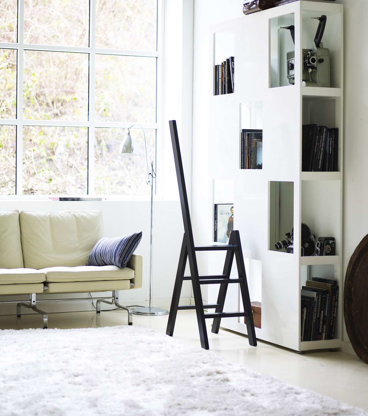 Schwarze Hindevadgaard Trittleiter im modernen Wohnzimmer mit Sofa, Bücherregal und Teppich für stilvolle Raumgestaltung.