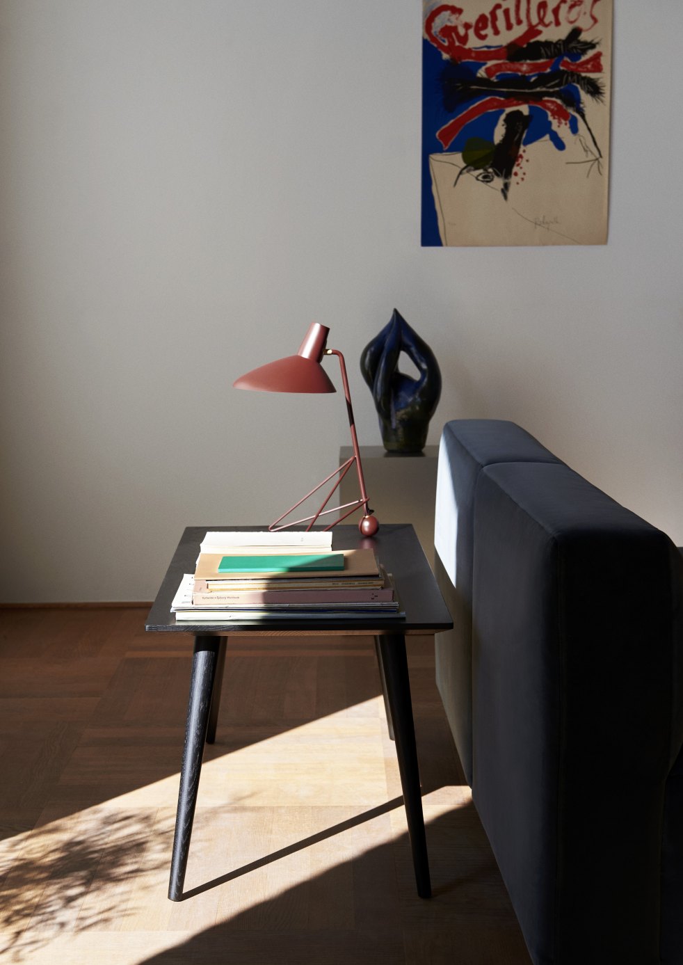 Schwarzer In Between Table Couchtisch von AndTradition mit Lampe und Büchern im Wohnzimmer.