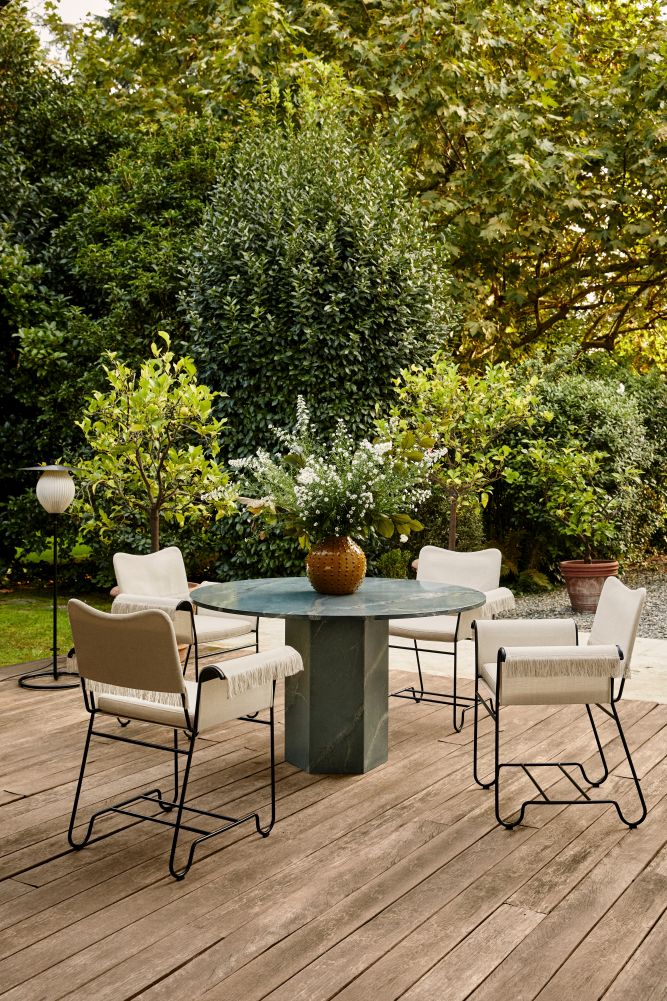 Gubi Epic Outdoor Esstisch 130cm mit Stühlen auf einer Holzterrasse im Garten.