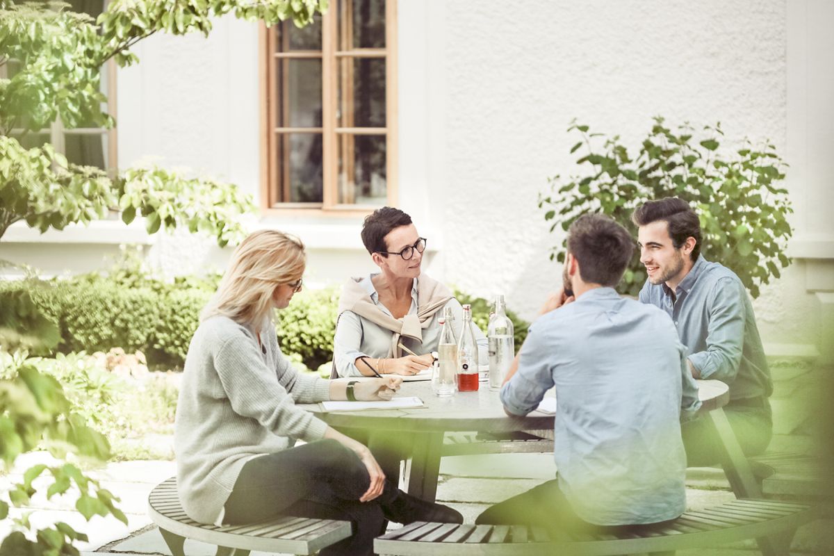 Gargantua Picknicktisch von Extremis im Garten: Gruppe von Personen sitzt entspannt an dem runden Outdoor-Tisch.