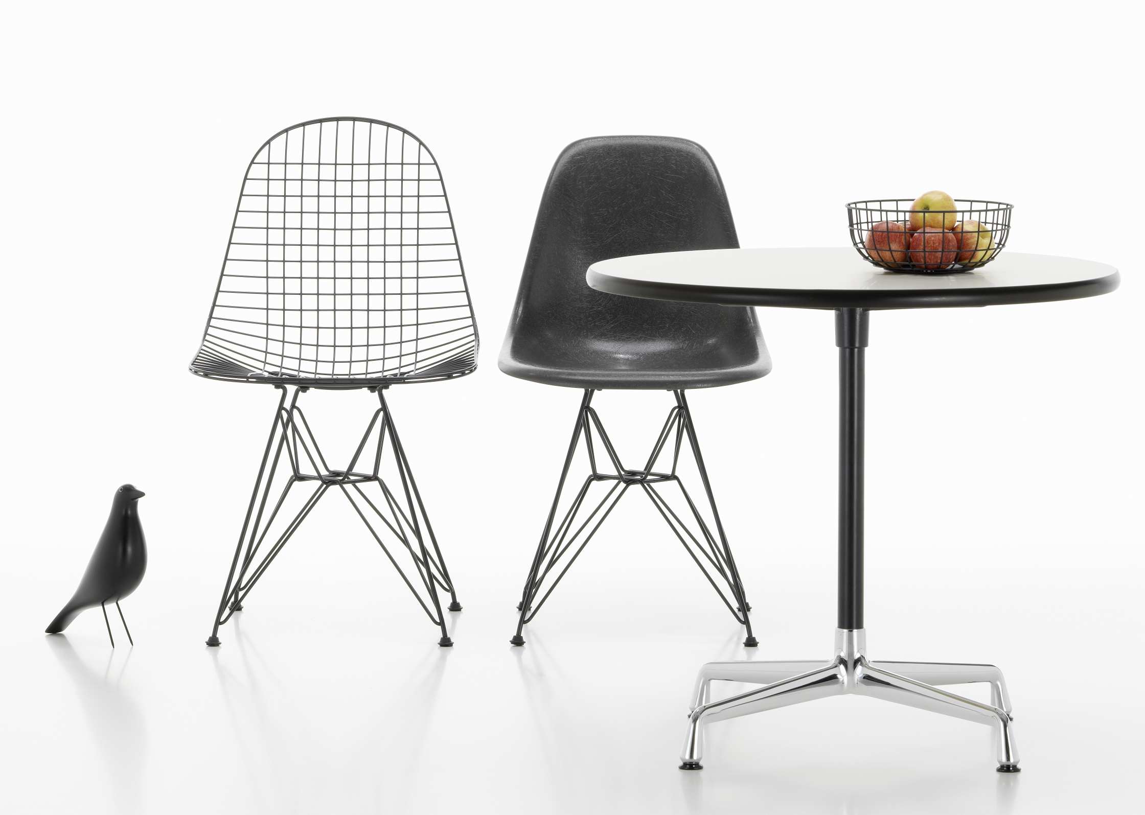 Eames Contract Table von Vitra mit zwei Eames Stühlen und Deko-Vogel auf weißem Hintergrund.