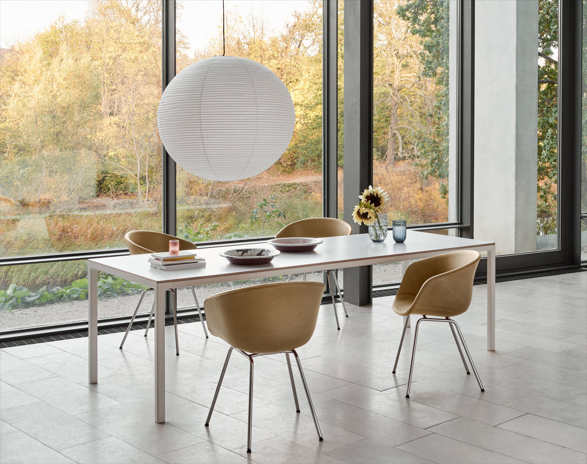 Esszimmer mit HAY About A Chair AAC27 Stühlen in Beige, weißem Tisch und großer Fensterfront.