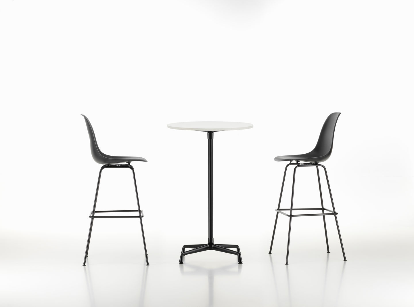 Zwei schwarze Eames Barhocker von Vitra mit einem runden, weißen Tisch in der Mitte.