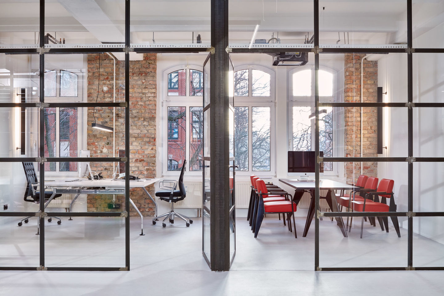 Modernes Büro mit Vitra Fauteuil Direction Sessel in Rot und Schwarz an einem Konferenztisch.