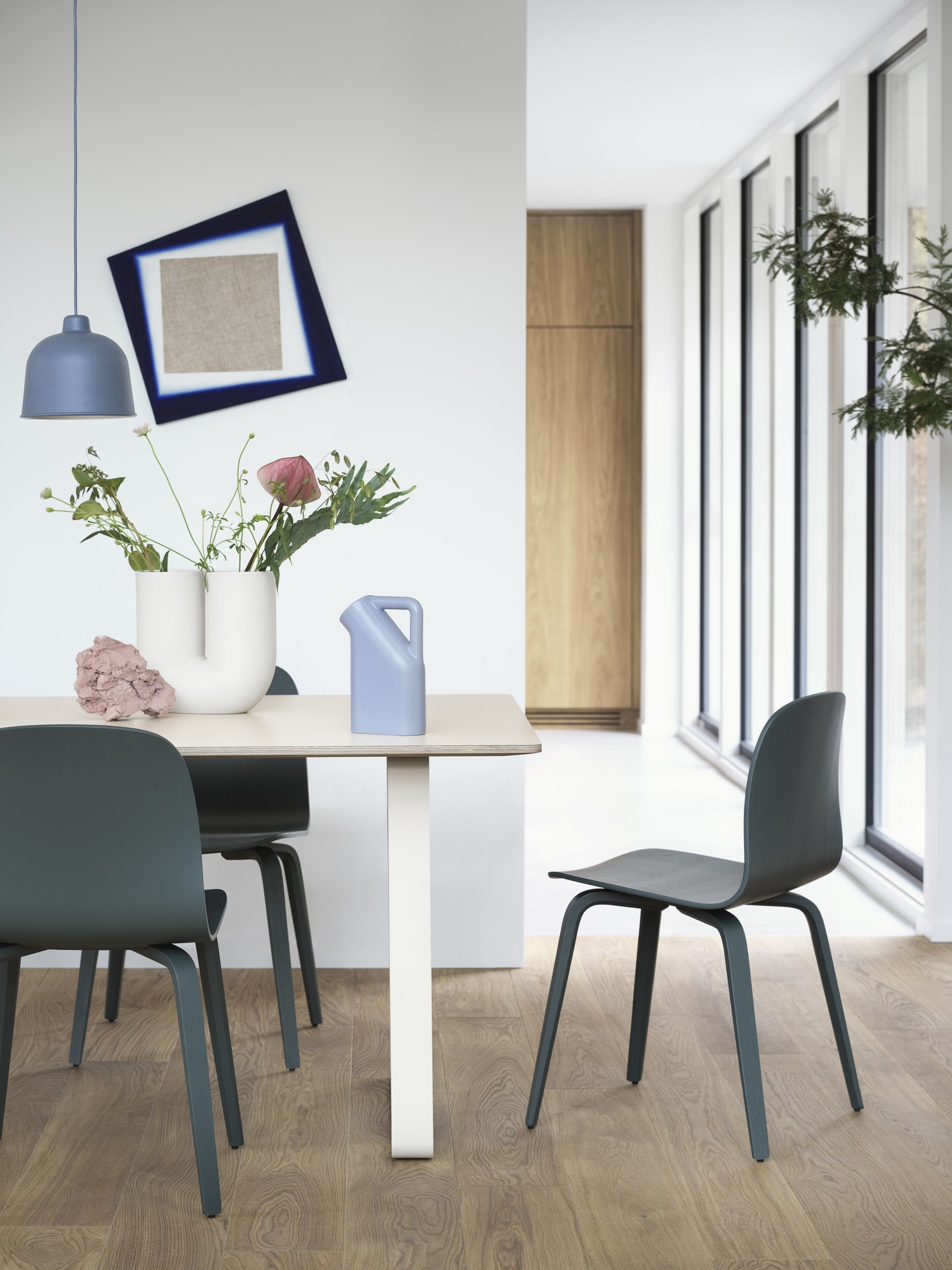 Esszimmer Interieur mit Esstisch, Stühlen und blauer Grain Pendelleuchte von Muuto über dem Tisch.