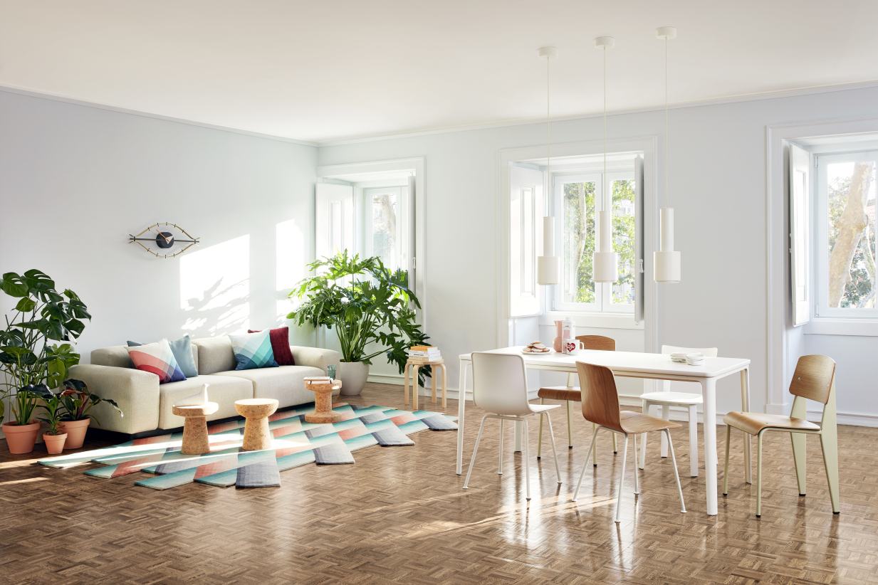 Helles Wohnzimmer mit Vitra Eye Clock Wanduhr über Sofa, Esstisch und Stühlen.