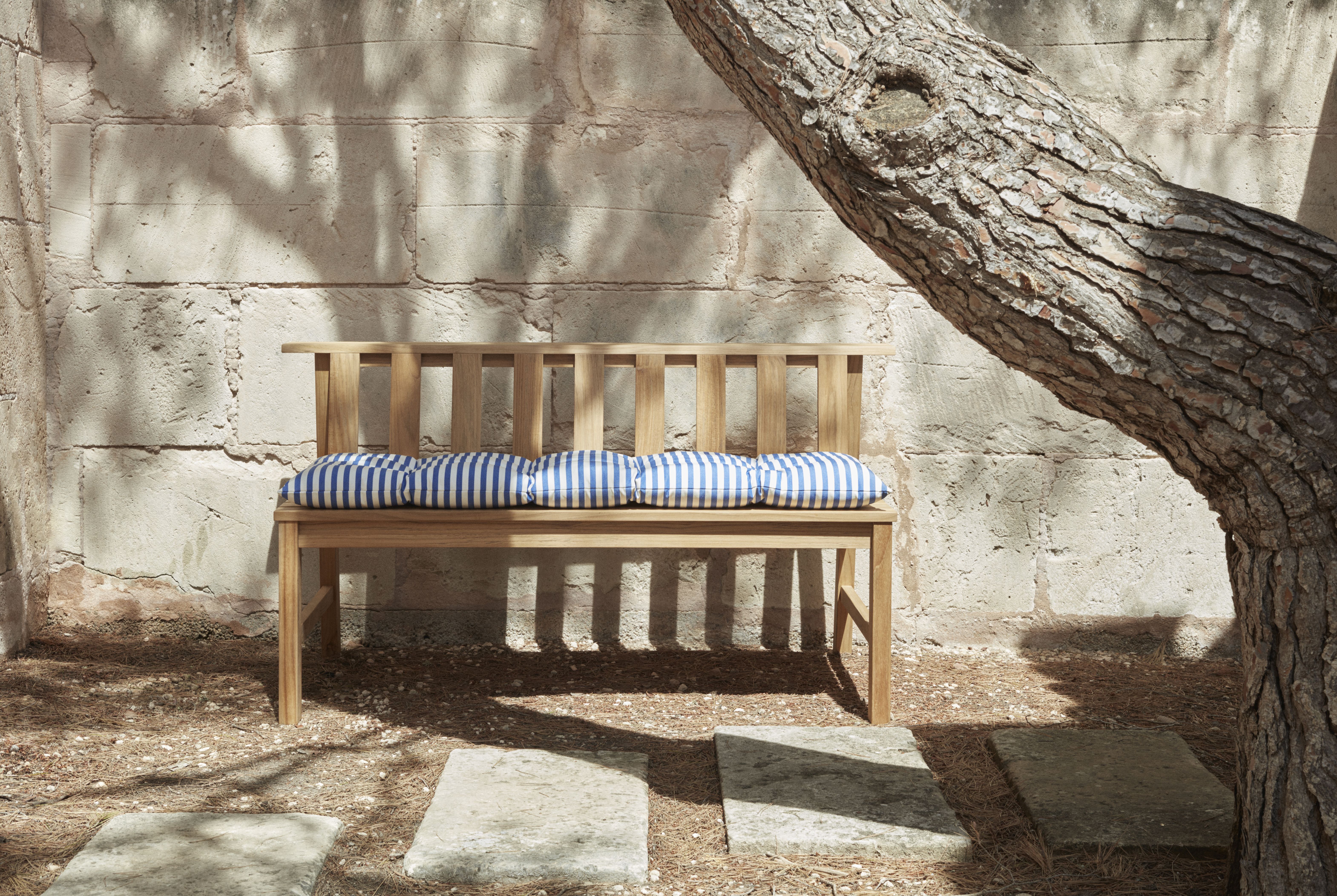Cadence Bank Teakholz Gartenbank von Skagerak by Fritz Hansen mit blau-weiß gestreiften Kissen.