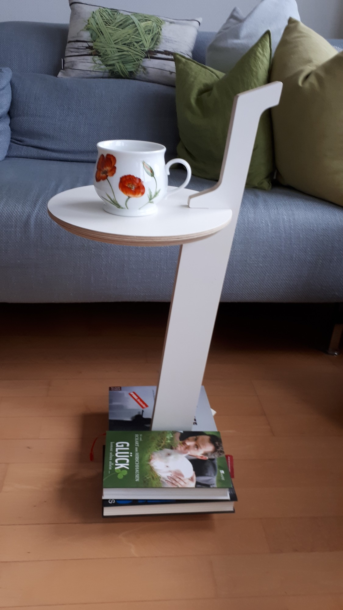 Lesestelle Bücherregal to go: Weißer Beistelltisch mit Ablagefläche und Bücherstapel als Basis, Tasse darauf.