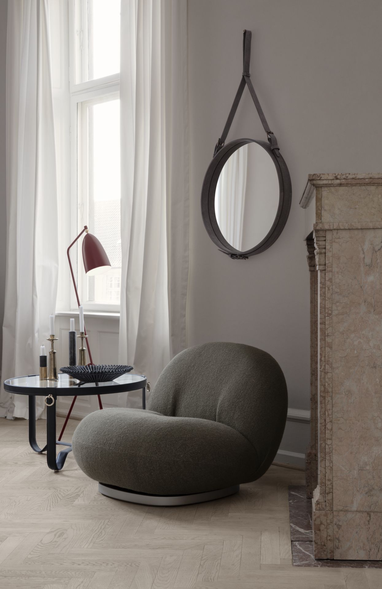 Gubi Gräshoppa Stehleuchte in Dusty Blue neben Sessel und Beistelltisch im Wohnzimmer.