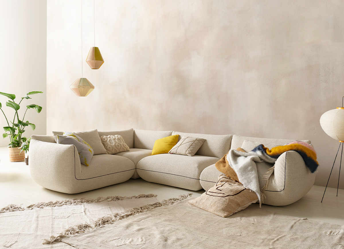 Beige modulare Eckcouch mit Kissen und Decken im Wohnzimmer, moderne Wohnzimmereinrichtung.