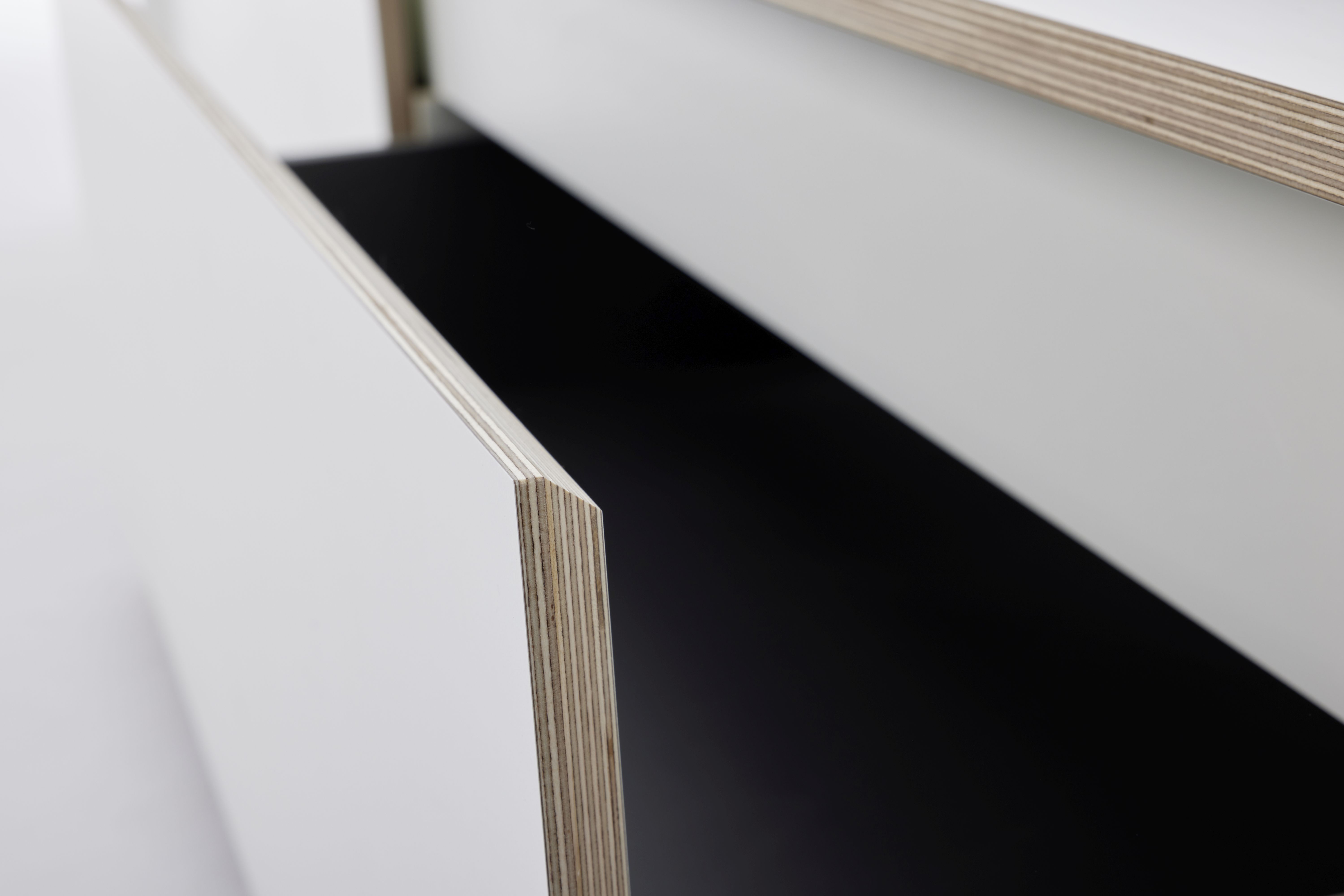 Detailaufnahme eines weißen Spaze Bettes von Müller Möbelwerkstätten mit offenem Schubladenelement aus hellem Holz.