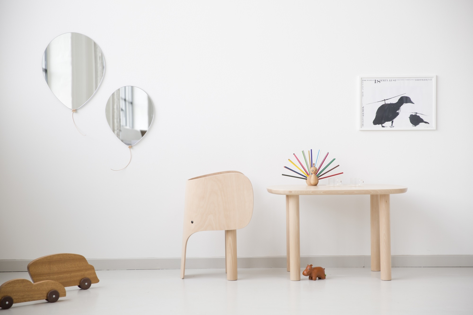 Heller Raum mit EO Elephant Chair Kinderstuhl aus Holz, Tisch, Spielzeugautos und Ballons als Spiegel.