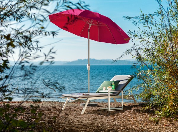 Weishäupl Pagodenschirm in Pink mit Liegestuhl und Beistelltisch am Seeufer für entspannte Stunden im Freien.