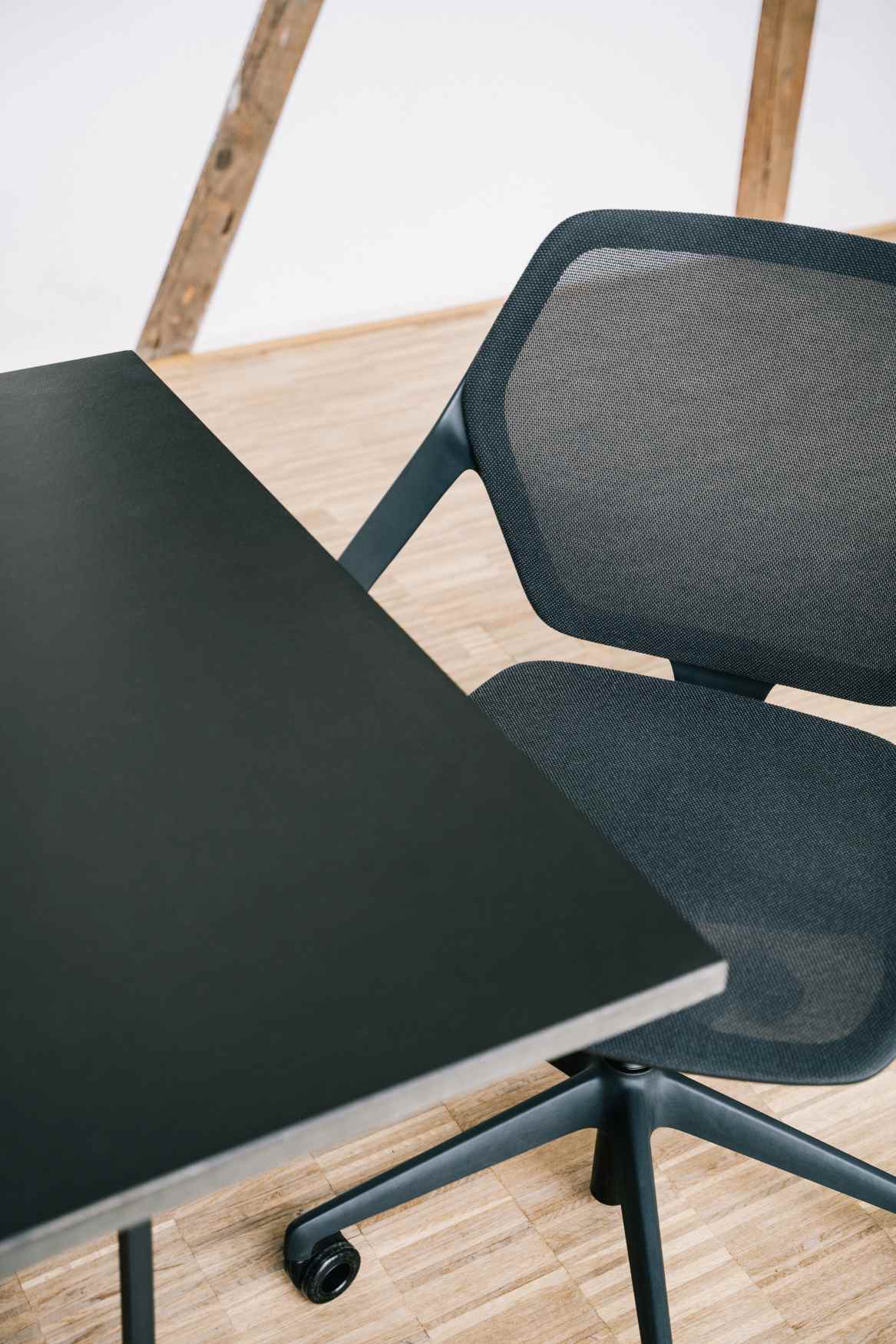 Detailaufnahme des Brunner Ray Work Drehstuhls mit Netzrückenlehne und schwarzem Fußkreuz neben einem Schreibtisch.