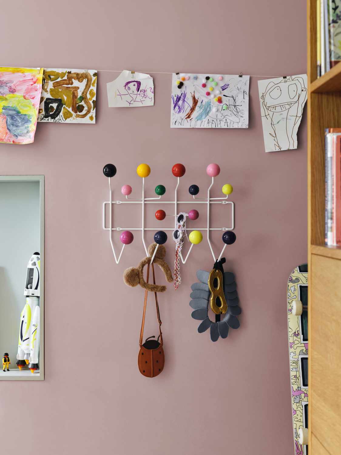 Eames Hang it all Garderobe von Vitra mit bunten Kugeln und Kinderzeichnungen an rosa Wand.