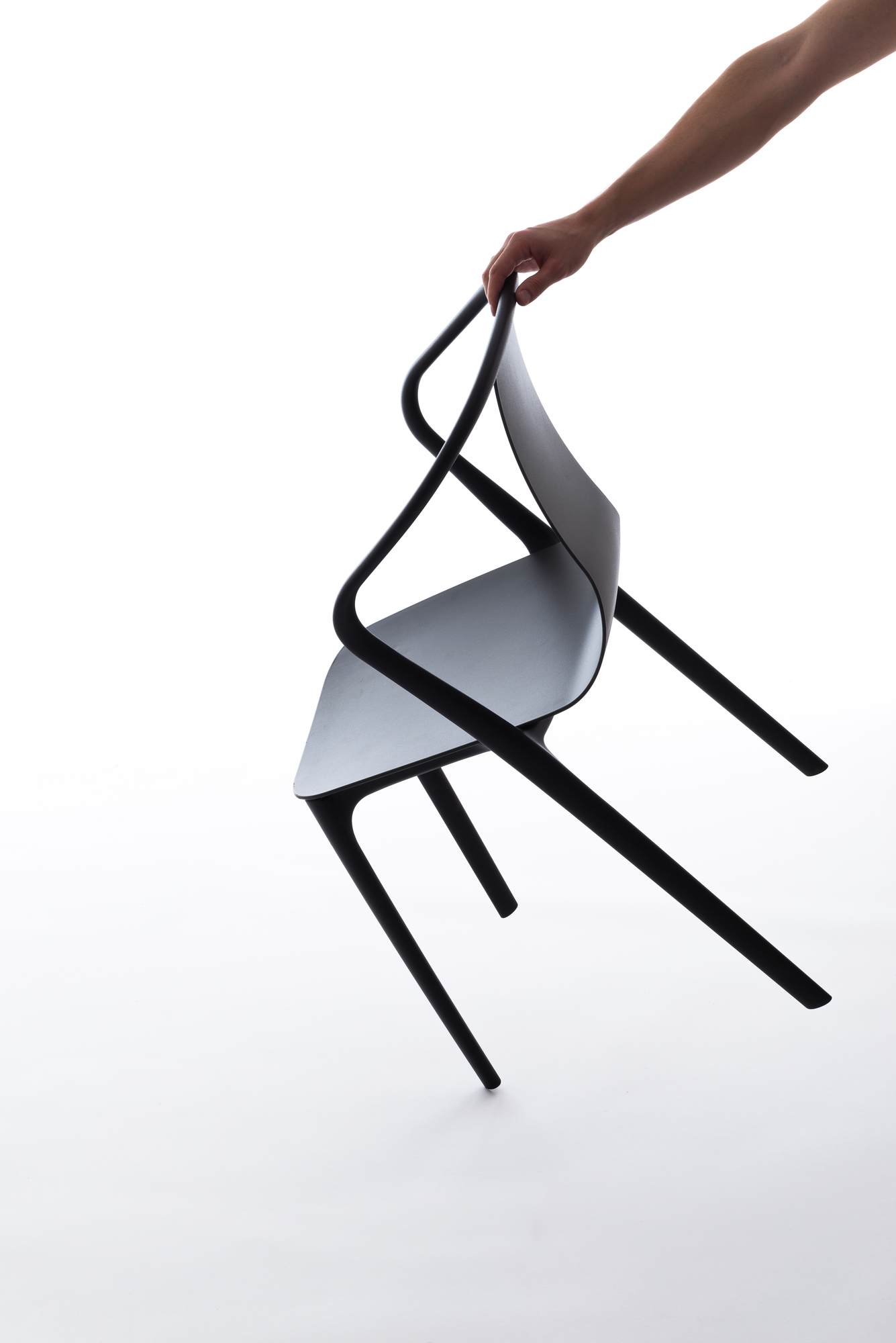 Schwarzer Belleville Chair Plastic Stuhl von Vitra wird von einer Hand gehalten, minimalistisches Design.