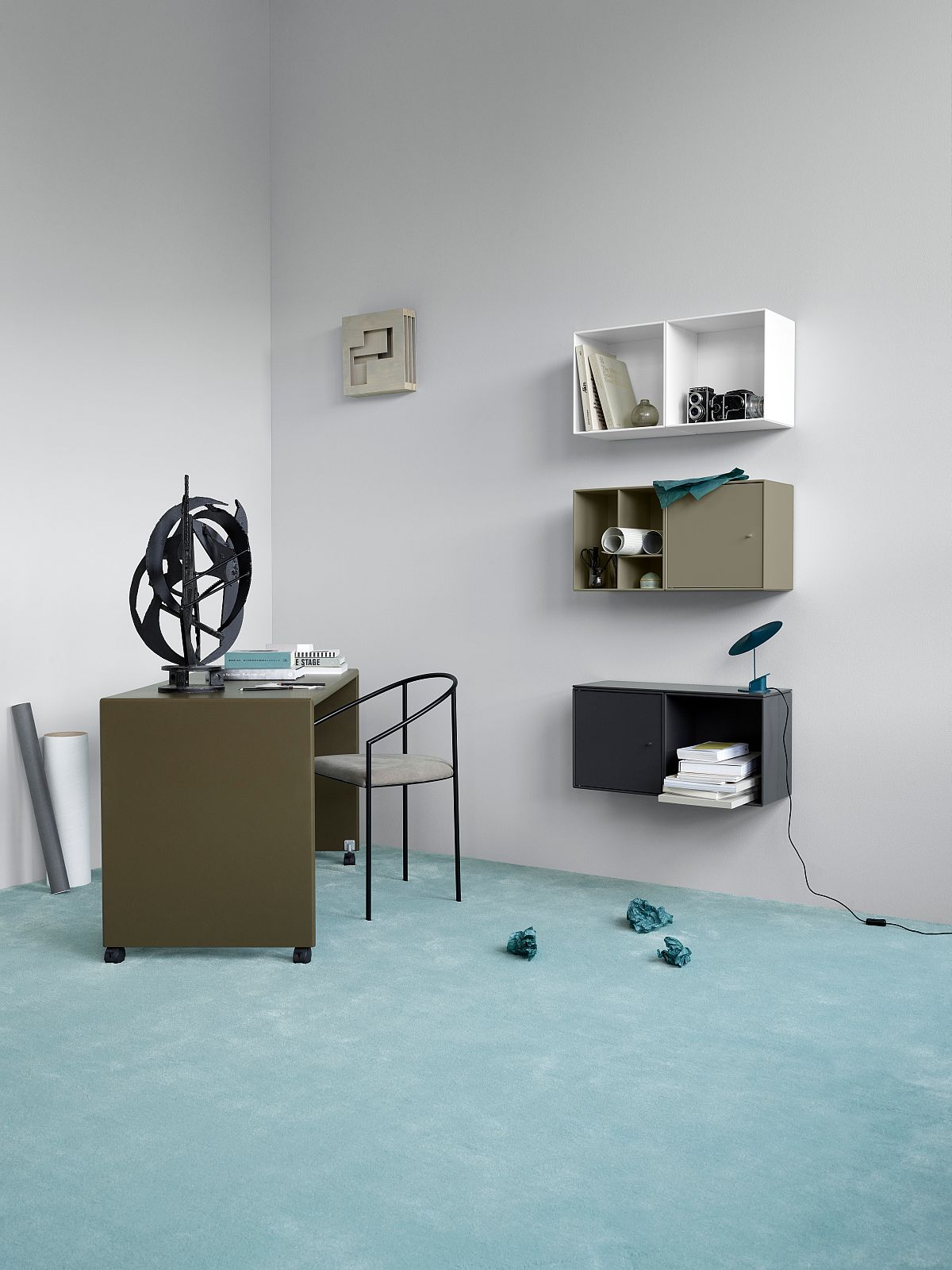 Modernes Büro mit Montana Mini Modul mit Tür, Schreibtisch, Stuhl und Wandregalen in verschiedenen Farben.