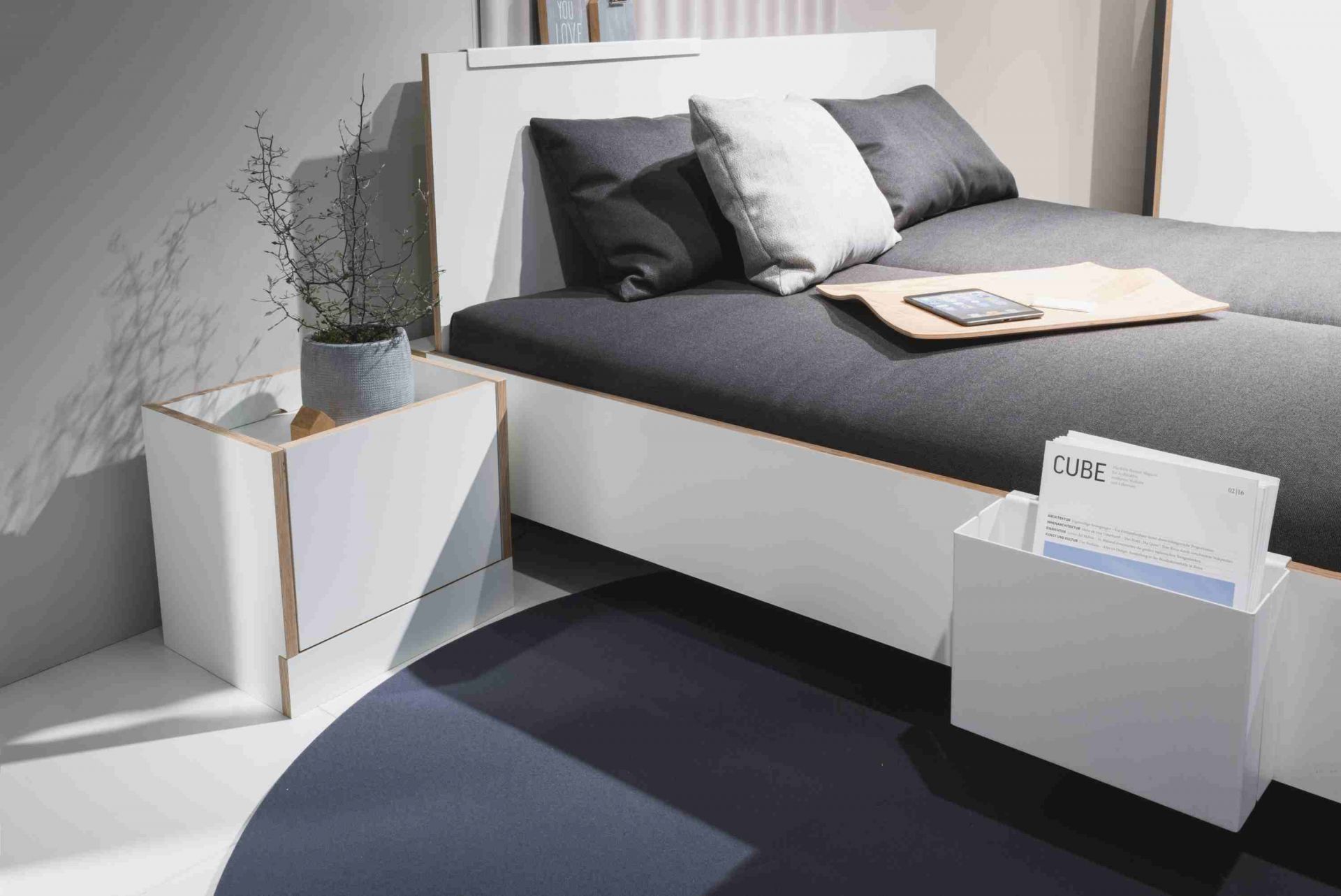 Modernes weißes Doppelbett mit grauer Matratze, Nachttisch und Dekoration für Schlafzimmer.