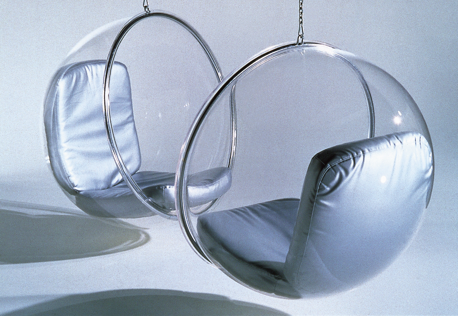Zwei transparente Bubble Hängesessel von Eero Aarnio mit silbernen Kissen hängen von der Decke.