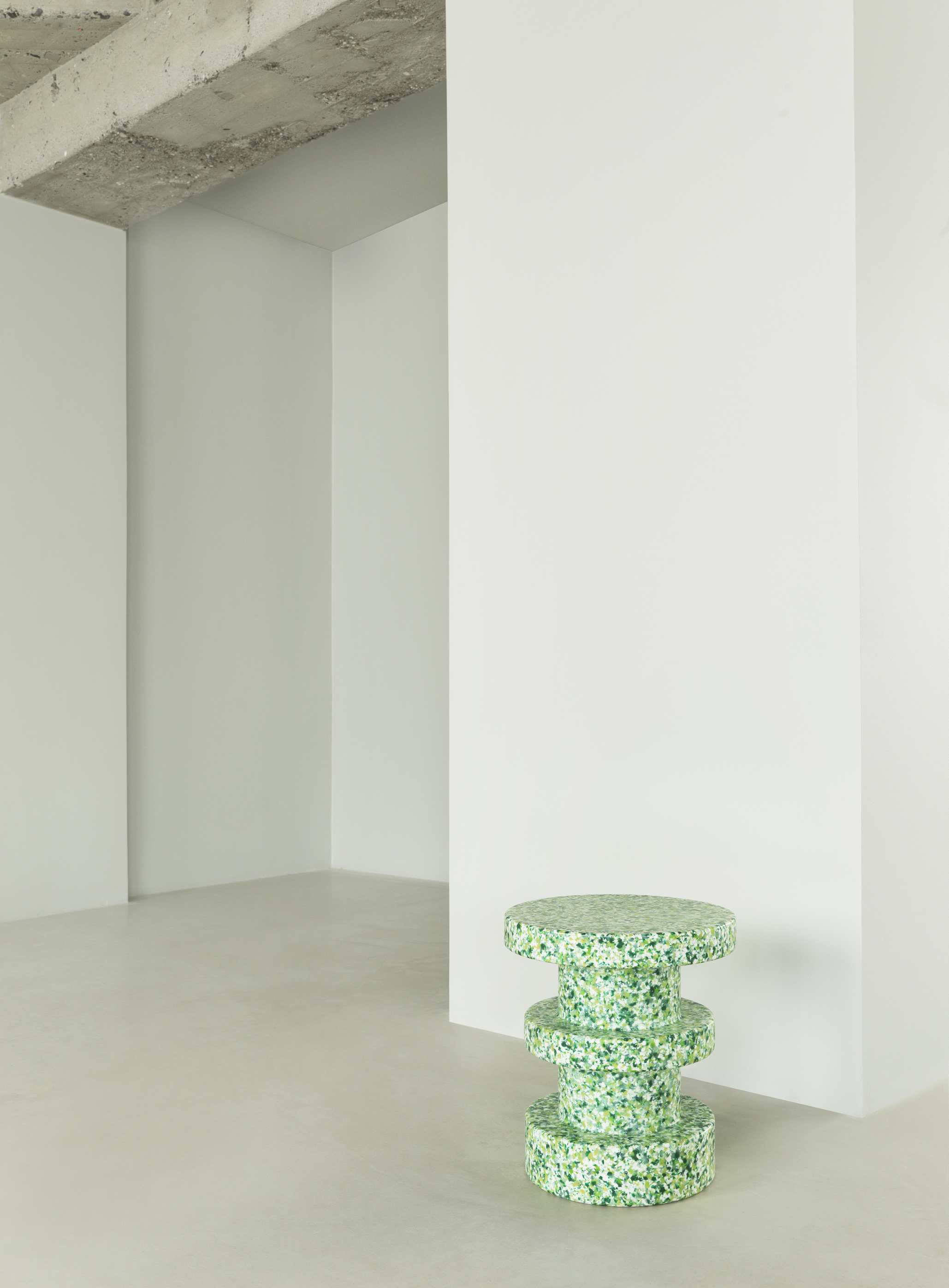 Normann Copenhagen Bit Stool Stack Hocker in Grün-Weiß gesprenkelt vor weißer Wand und Betonboden.