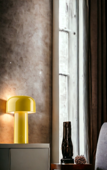 Gelbe Bellhop Akku Tischleuchte von Flos mit USB-Kabel auf einem Nachttisch.