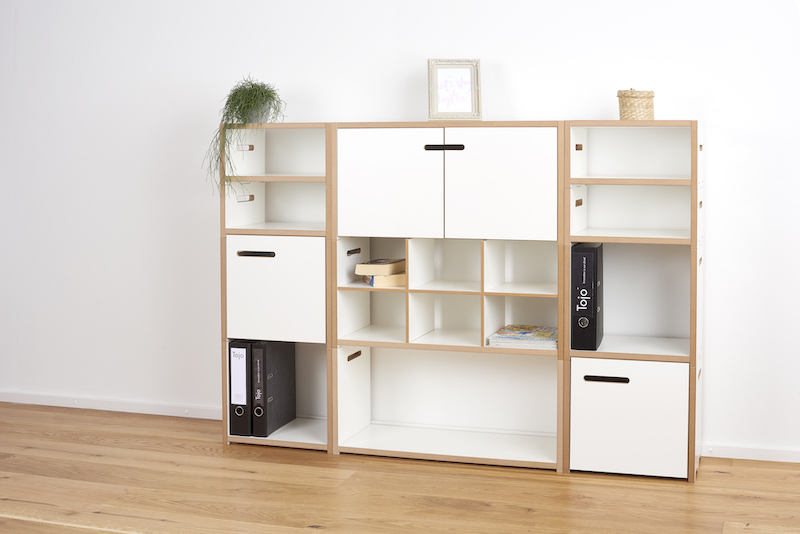 Tojo Halbstark Regalsystem: Modulares, niedriges Anbaumodul mit weißen Fächern und Schrankelementen für Büro und Wohnraum.
