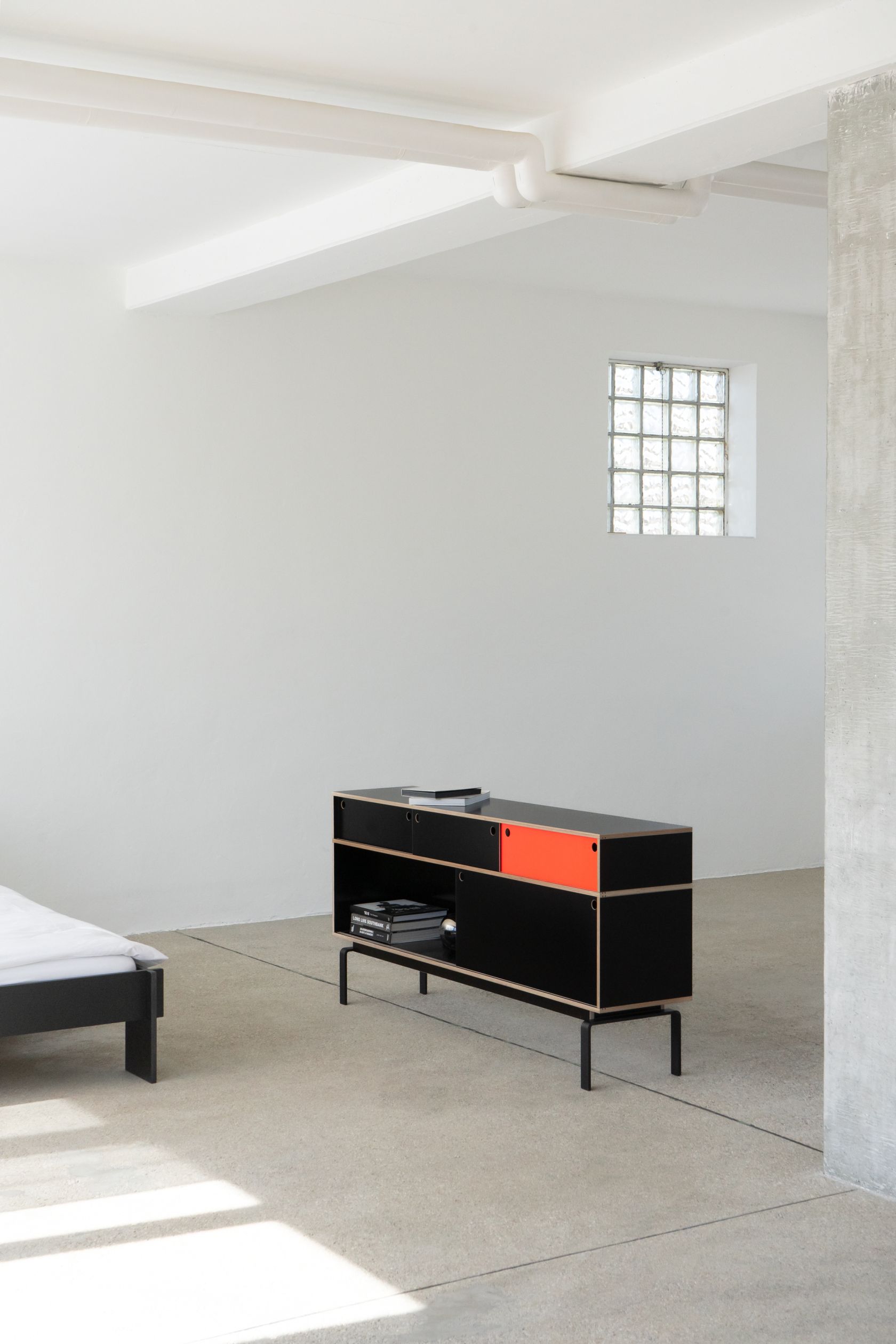 Egal Sideboard von Nils Holger Moormann, schwarz mit orangefarbener Tür, modernes Designmöbel für Wohnzimmer.
