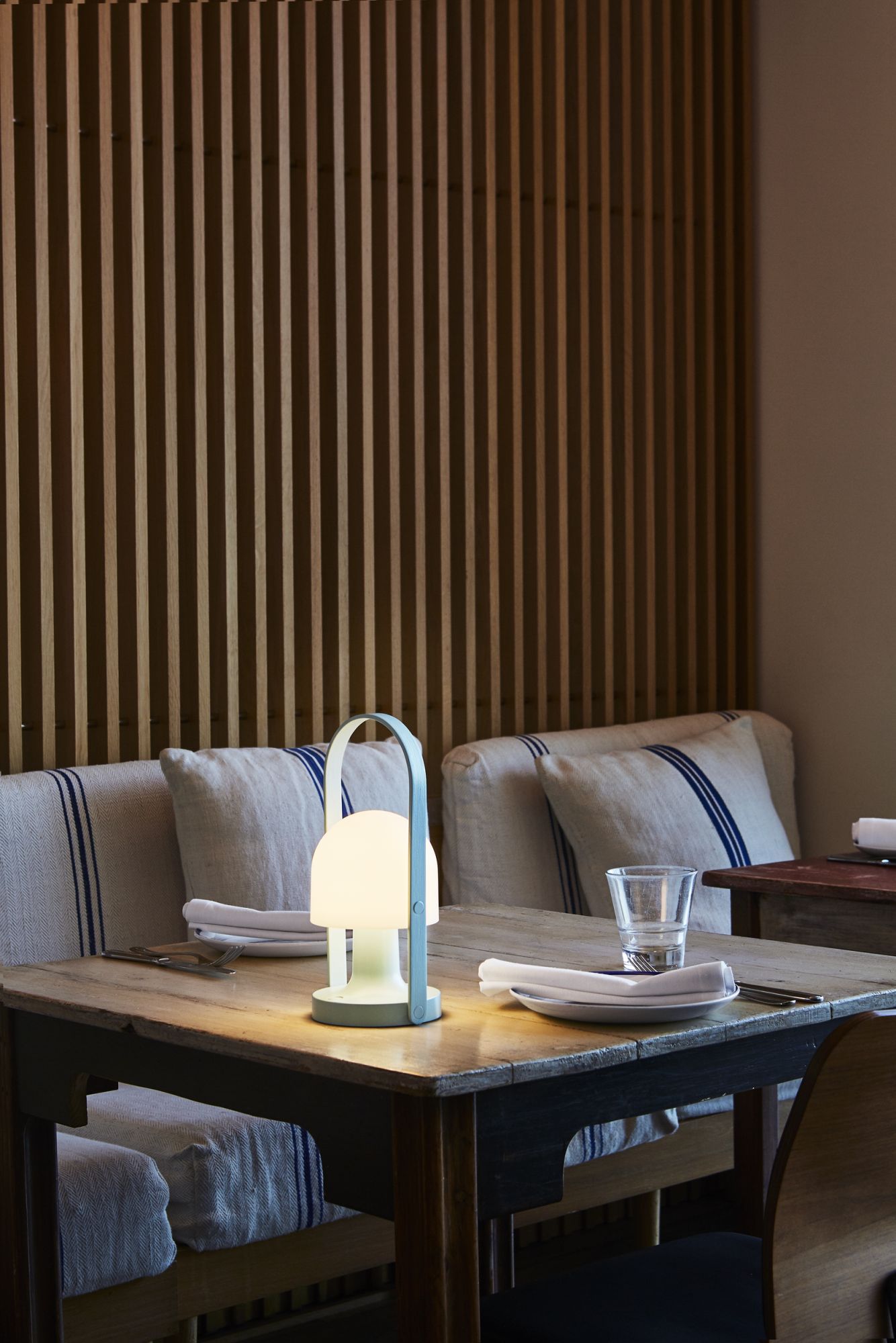FollowMe LED Tischleuchte in Terrakotta auf gedecktem Holztisch mit Besteck und Glas.