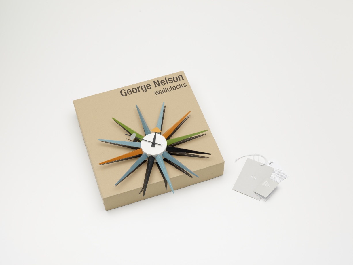 Mehrfarbige Sunburst Clock Wanduhr von Vitra auf Karton mit Etikett, modernes Designobjekt für Wohnzimmer.