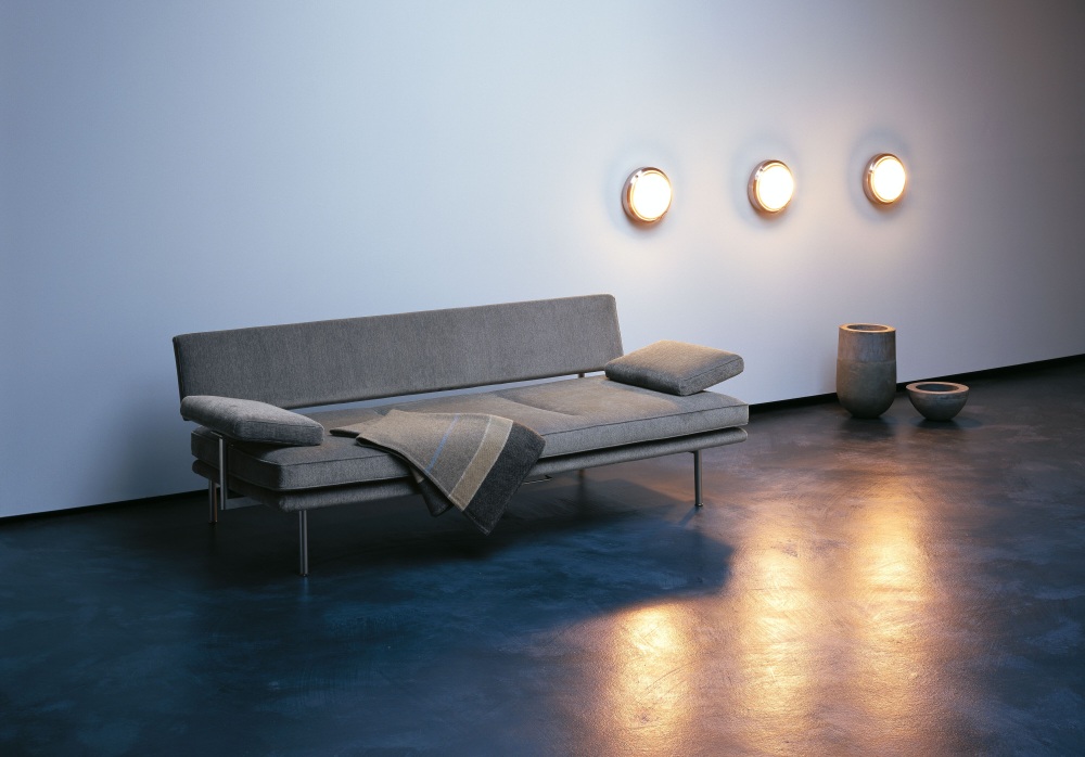 Graues Walter Knoll LIVING PLATFORM Sofa mit Funktionsarmlehnen und Decke auf blauem Boden.