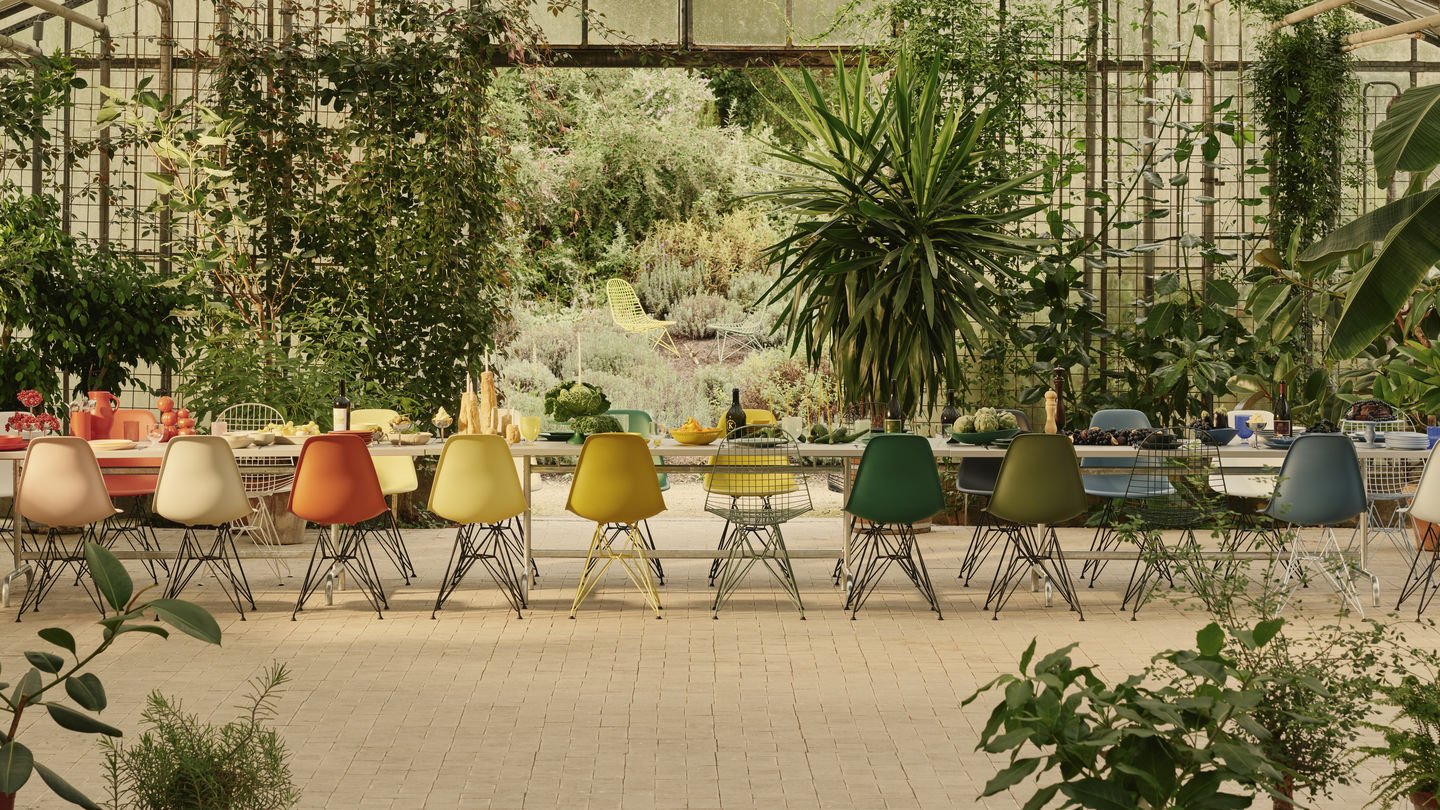 Eames Plastic Side Chair DSR Stühle von Vitra in verschiedenen Farben an langem Esstisch.