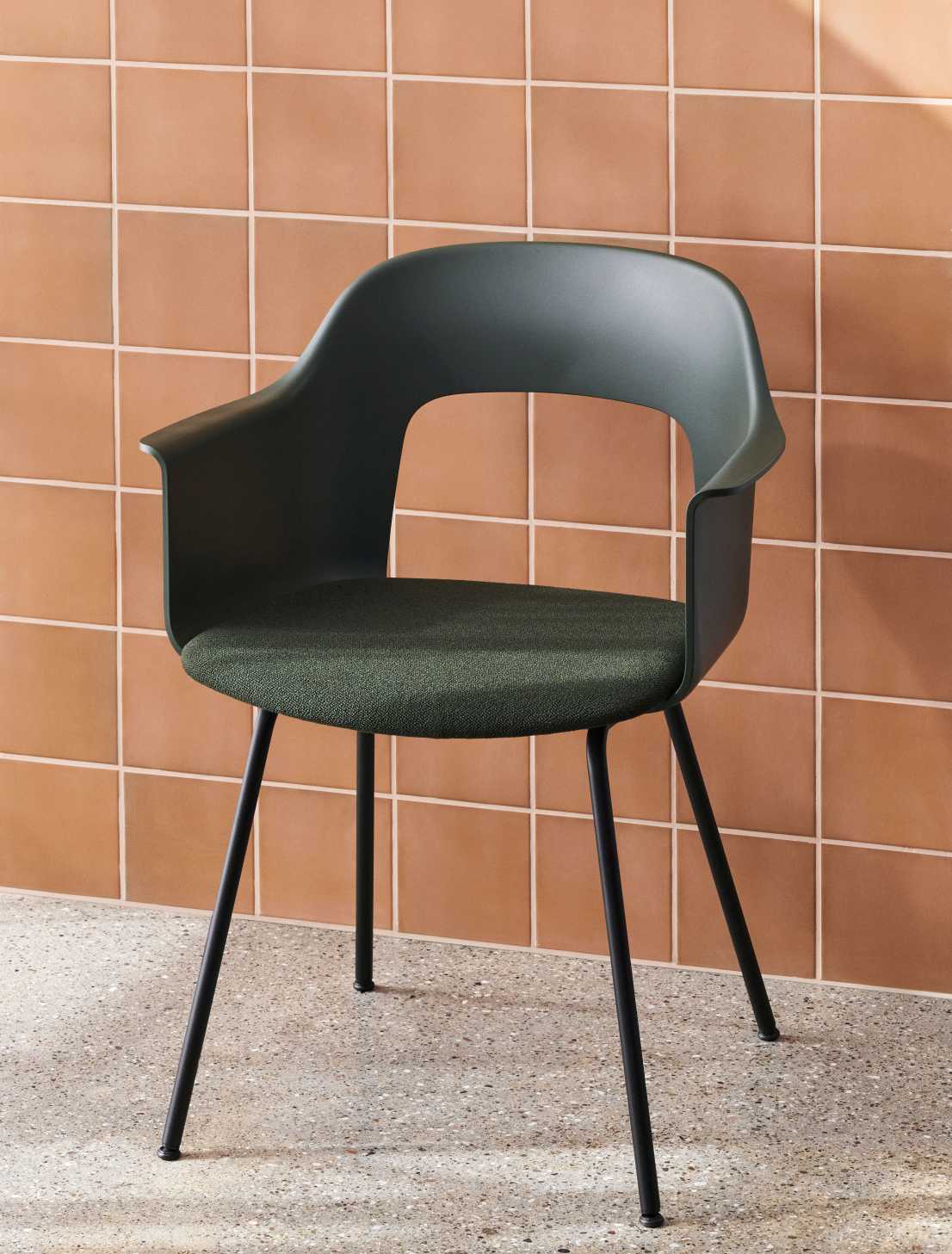 Layout Armchair 213 von Hay, grüner Armlehnstuhl mit schwarzem Gestell und textiler Sitzfläche vor Wandfliesen.