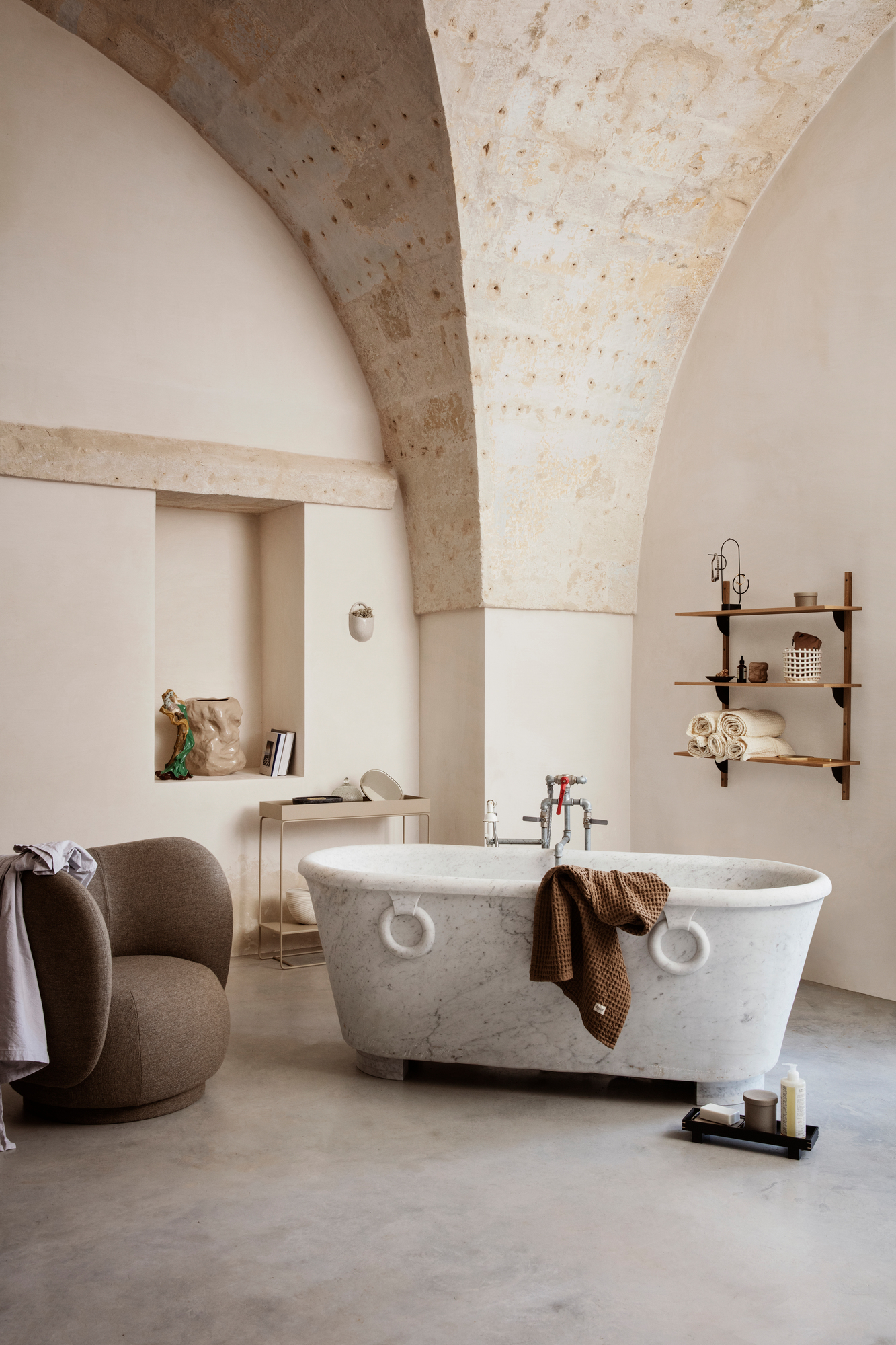 Innenaufnahme eines Badezimmers mit Rico Lounge Chair Sessel von Ferm Living und Marmorbadewanne.
