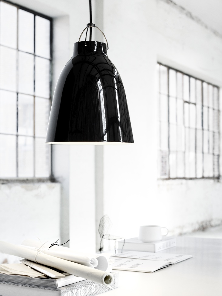 Schwarze Caravaggio Pendelleuchte von Fritz Hansen über einem Schreibtisch in einem hellen Raum mit Fenstern.