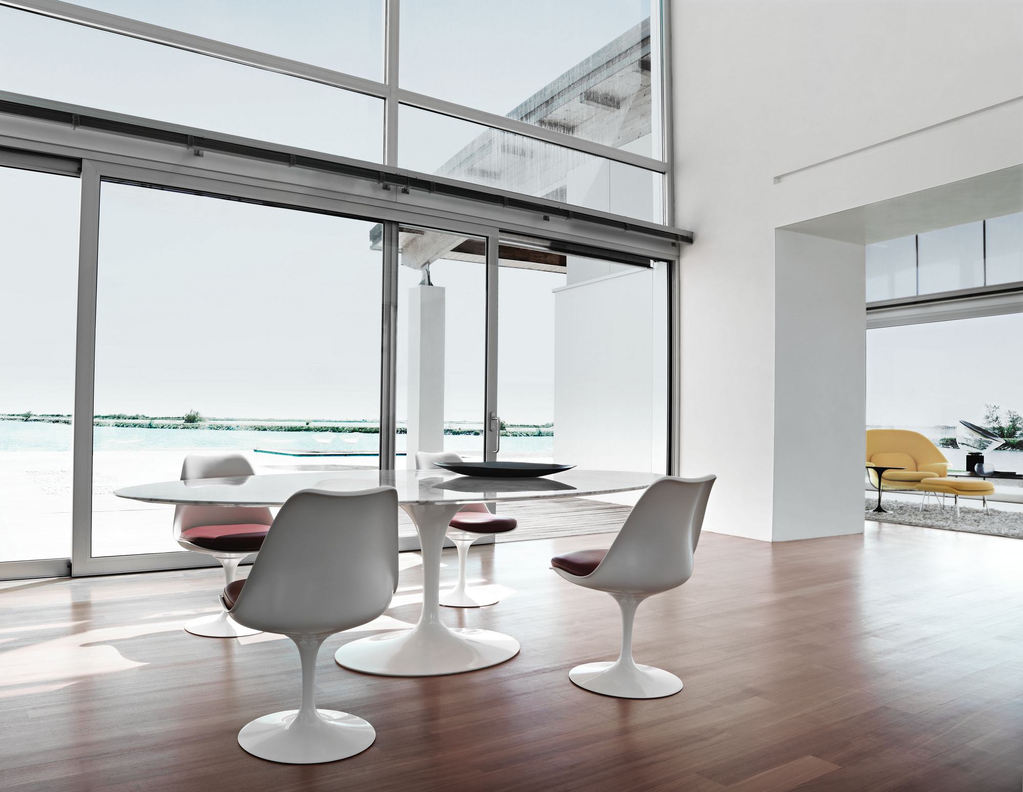 Esszimmer mit Marmortisch und vier weißen Tulip Chair Stühlen von Knoll International mit braunen Sitzkissen.