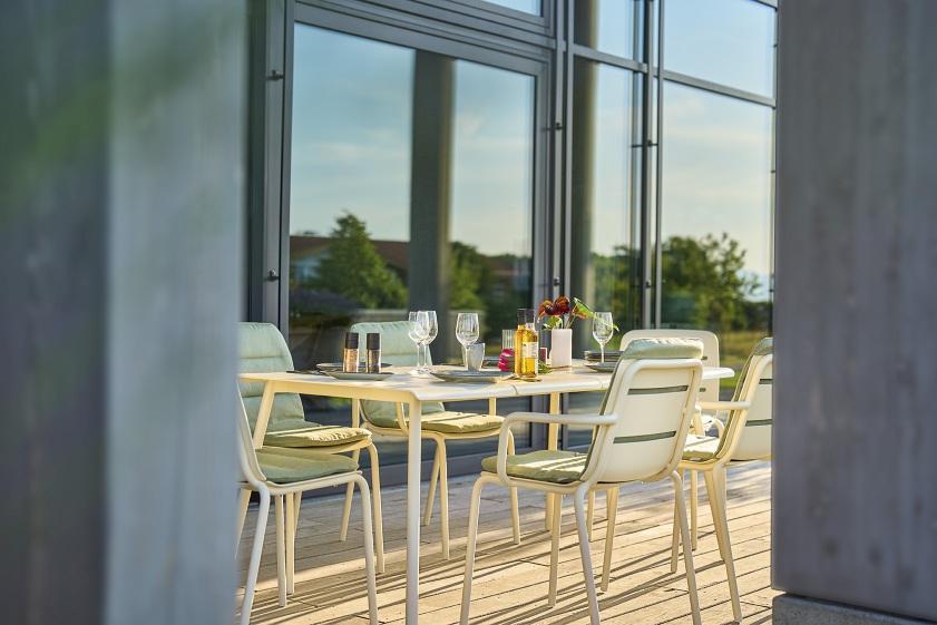 Weishäupl Vapio Stuhl Outdoor: Gartengarnitur mit weißen Stühlen und Tisch auf einer Terrasse.