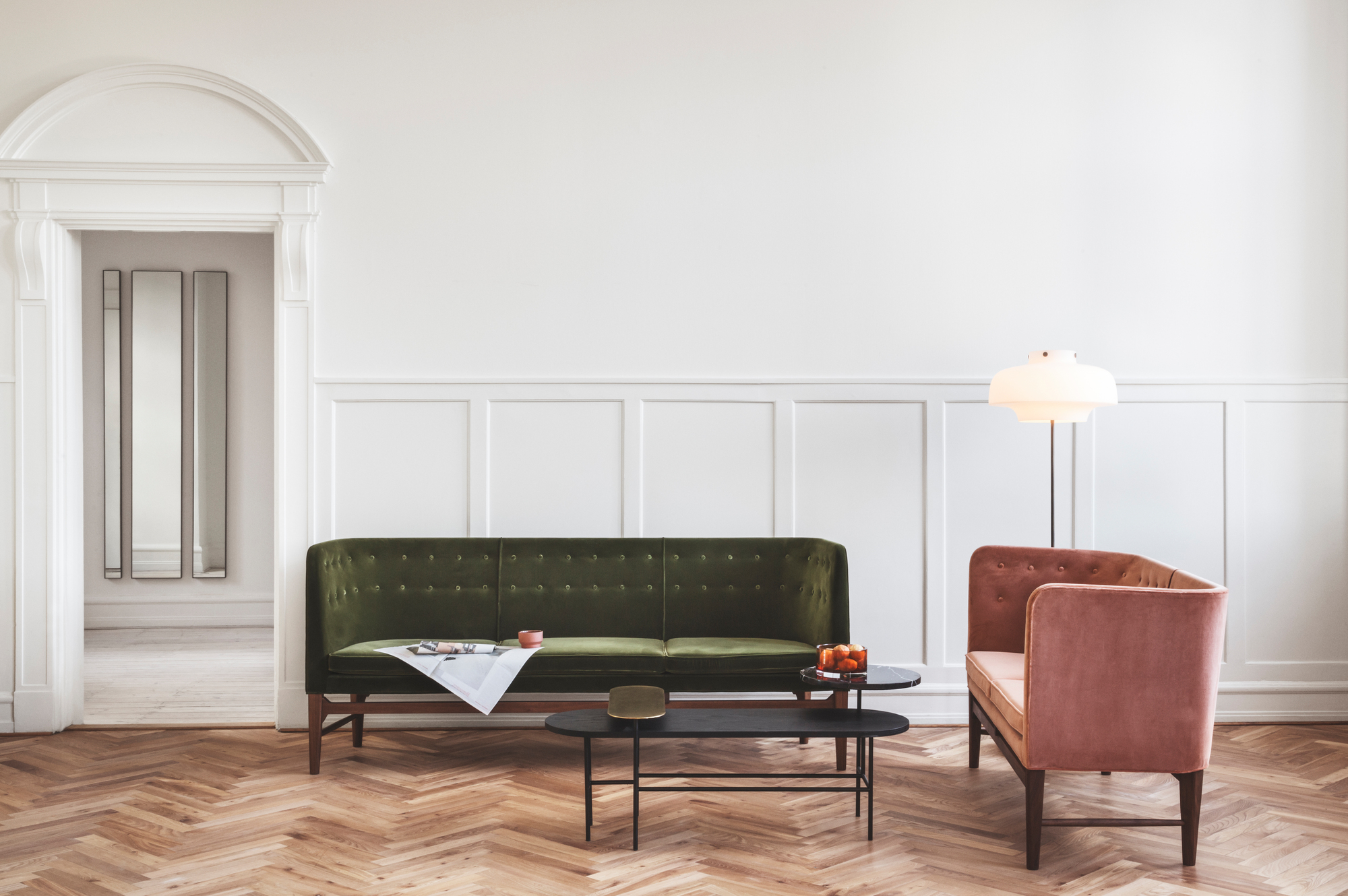 Elegantes Wohnzimmer mit grünem Mayor 2-Sitzer Sofa von AndTradition und rosa Sessel auf Parkettboden.