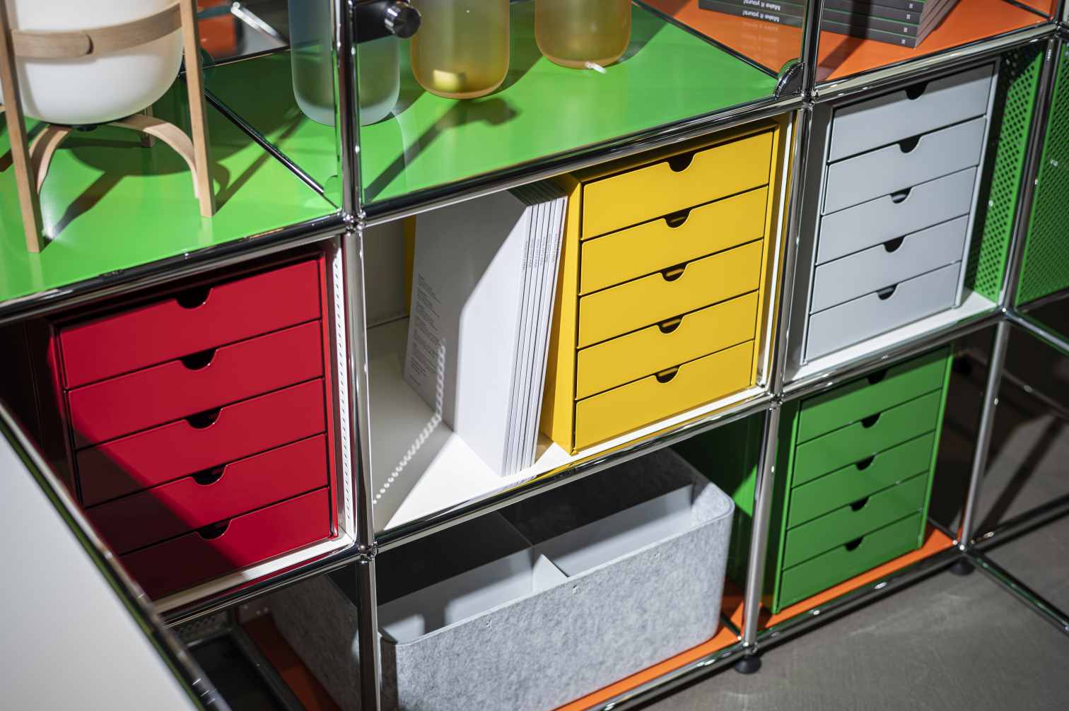 Detailaufnahme von USM Haller Möbelbausystem mit Inos Kastensets in Goldgelb, Rot, Grün und Grau für Büro und Home Office.