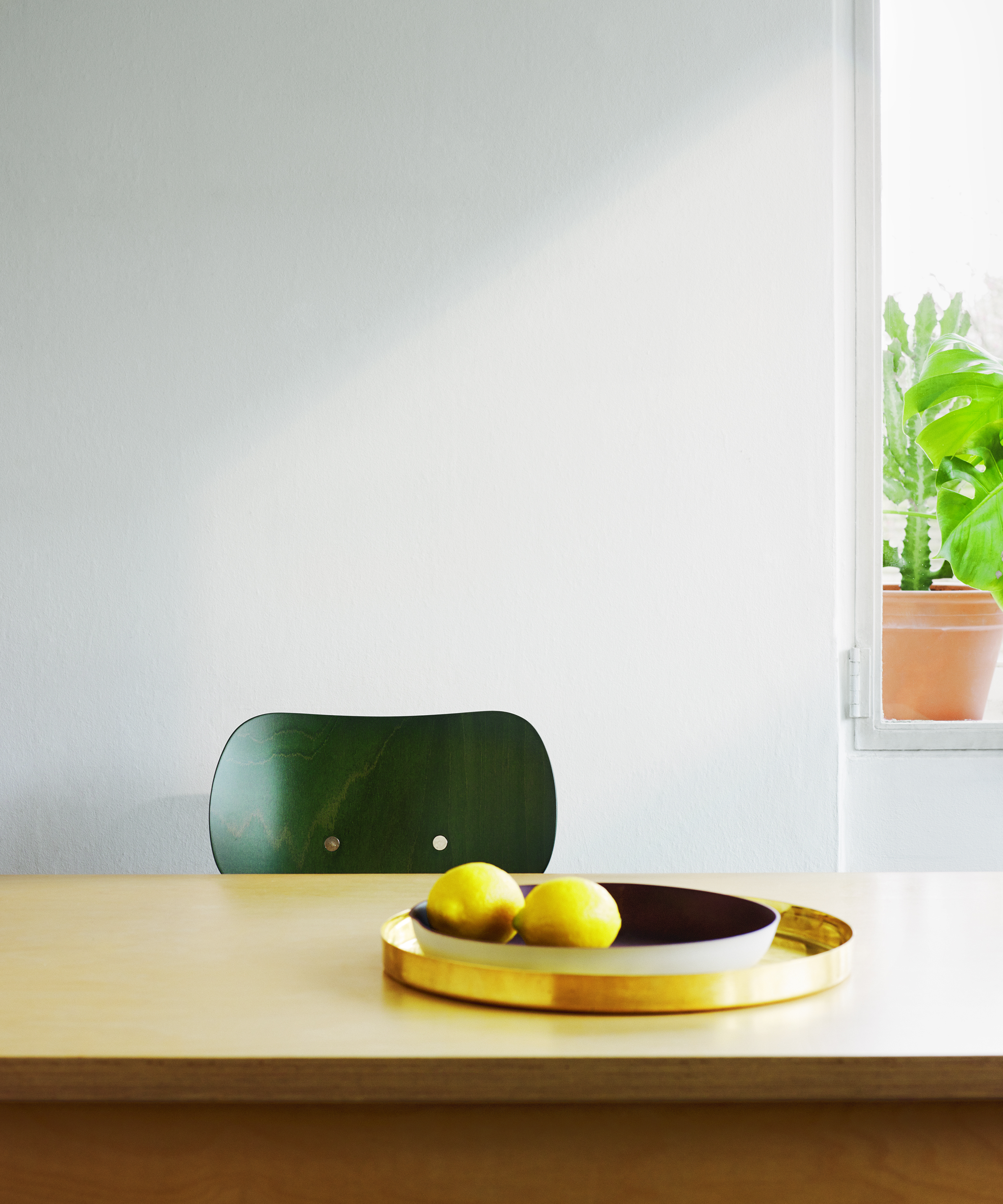 SE 68 Stuhl von Wilde+Spieth, dunkelgrüne Sitzschale, minimalistisches Design mit Zitrone auf Tisch.