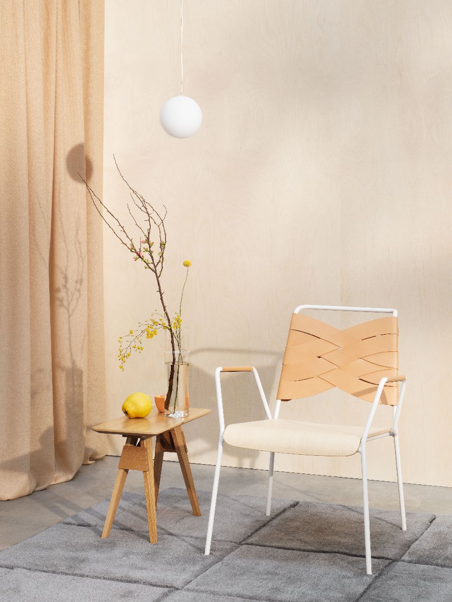 Helle Inneneinrichtung mit Design House Stockholm Luna Lampe, Tisch mit Dekoration und modernem Sessel.