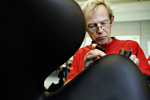 Handwerker fertigt einen schwarzen Swan Chair Sessel von Fritz Hansen in Handarbeit.