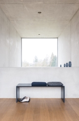 Schwarze Schönbuch Sitzbank mit Kissen vor Fenster, minimalistisches Design für Flur und Eingangsbereich.