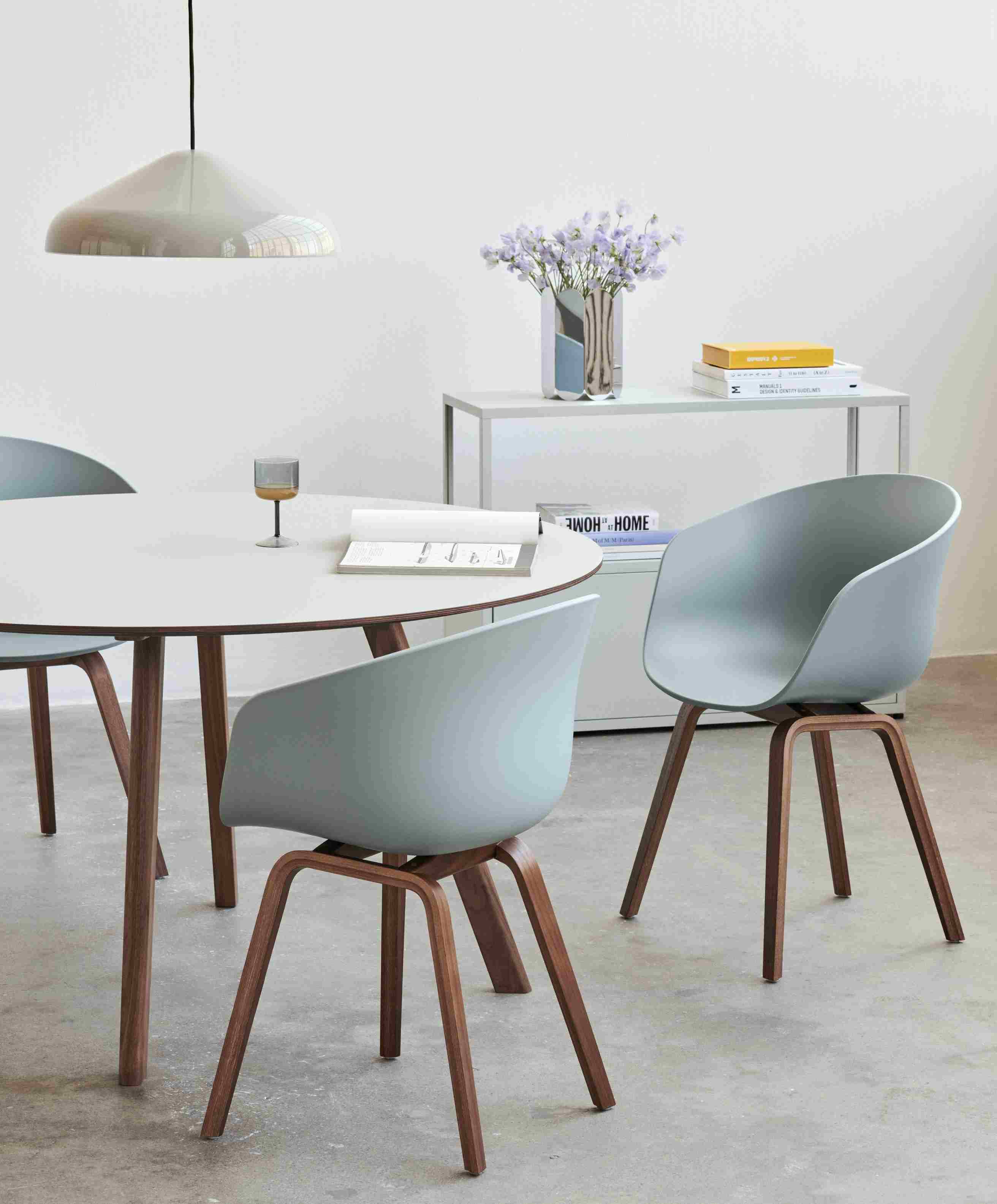 Esszimmer mit rundem Tisch, Stühlen mit Holzbeinen und Hay Arcs Vase L Mirror im Hintergrund.